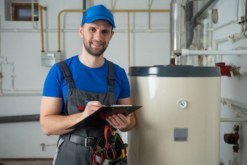 Technician servicing an hot water heater. Man check equipment of the boiler-house - thermometer.