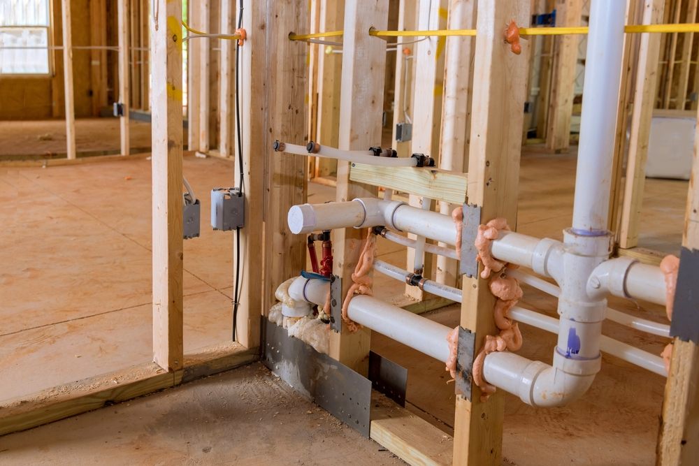 How Does Poly B Plumbing Compare to Other Piping Materials? PEX. Home construction with hot red and cold blue pex pipe layout in new bathtub house PVC waste water system. 