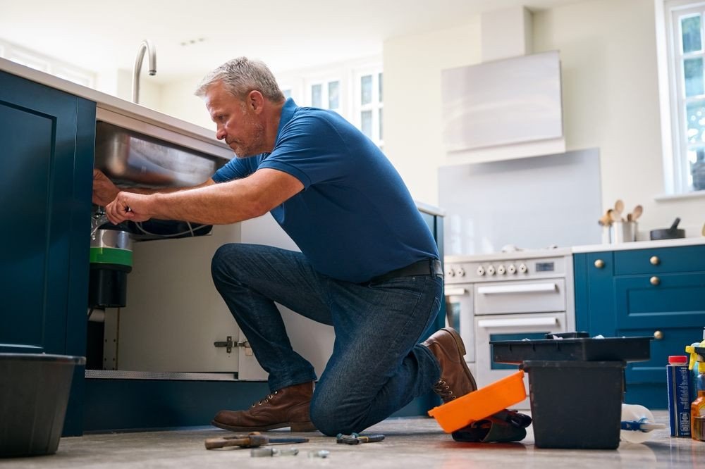 How Calgary Residents Reduce Water Usage Through Efficient Plumbing Practices? Water Usage. Mature Male Plumber Fixing water waste In Domestic Kitchen Sink.